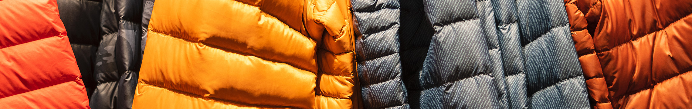 Winter puffer coats hung in a closet in a variety of colors