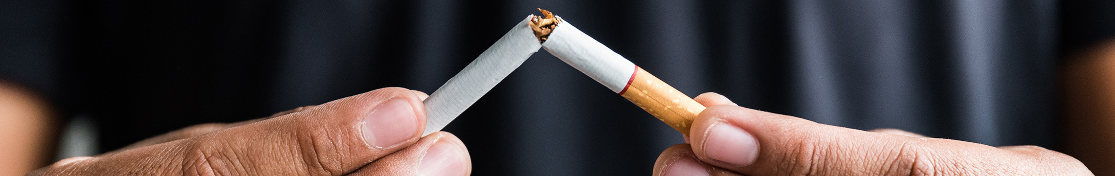 Man snapping cigarette in half with determination to quit smoking