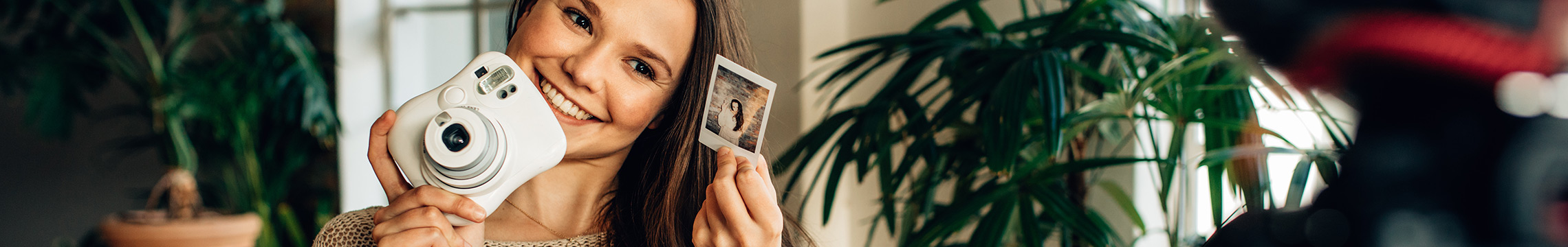 Woman blogger recording video while showing off polaroid camera