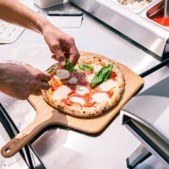 Garnishing pizza on Ooni 12'' bamboo peel