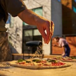 Man adding seasoning to a homemade pizza