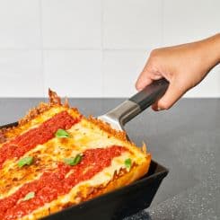 Detroit style pizza being taken  out of pan 