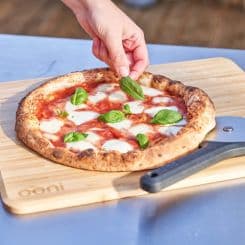 Adding toppings to a pizza ontop of prep lid