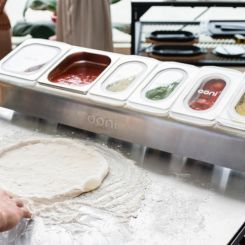 Pizza dough in front of topping station