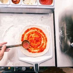 Adding pizza sauce to dough ontop of Ooni 14'' perforated pan