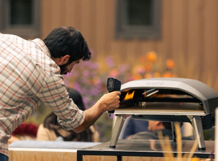 Man checking ooni pizza oven temperature with IR thermometer 