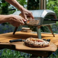 Pizza being seasoned on Ooni 12'' Bamboo peel