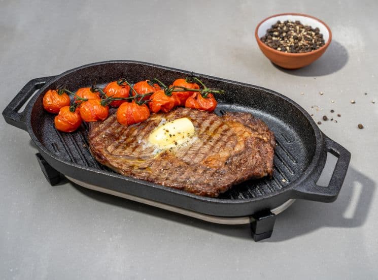 Meat and tomatoes sitting in Ooni grizzler pan