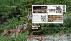 OFDC cover with four stamp designs over an eastern wolf photo, plus “Wolves,” day-of-issue, credits, barcode, and pawprint cancel mark.