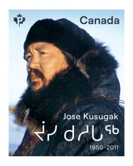Stamp with &quot;Jose Kusugak,&quot; and Indigenous language text with a photo of him looking in the distance, in front of a blue sky landscape. 
