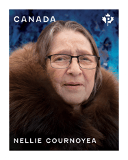 Stamp with “Nellie Cournoyea” text and a portrait of her looking forward, wearing glasses, with a fur-collared coat and a mottled blue background. 