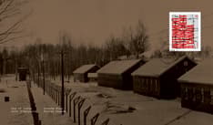 Recto de l’enveloppe orné d’une photo sépia d’un camp d’internement bordé d’une clôture barbelée l’hiver et du timbre dans le coin supérieur droit.