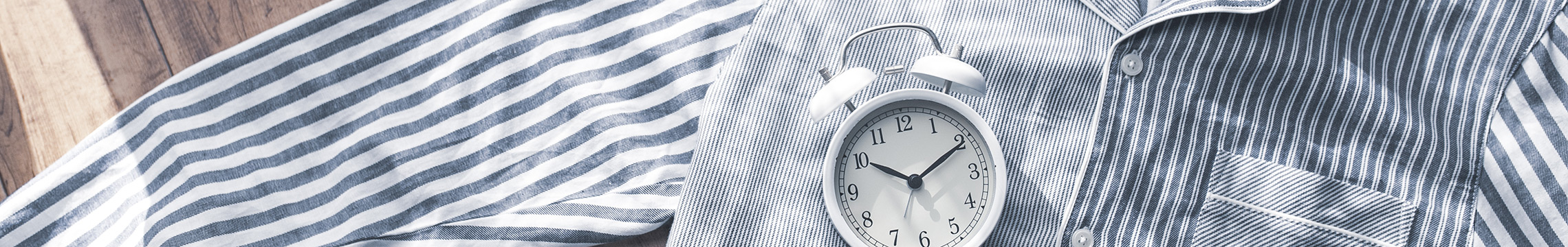 Blue and white striped button down pajama shirt with an alarm clock resting on top