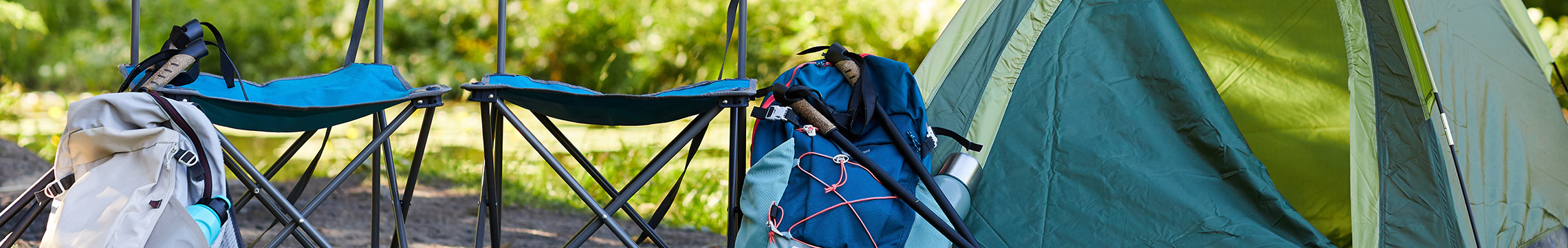 Tent, chairs, and other camping equipment set up on a grassy site on a sunny day