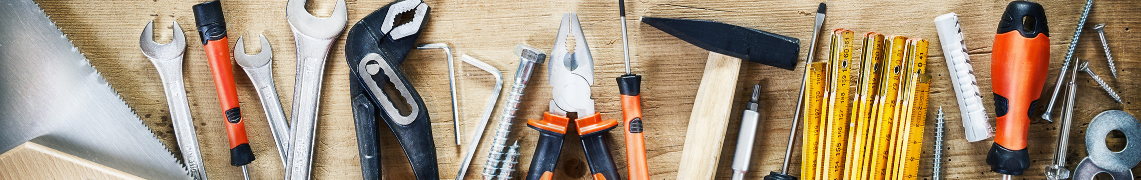 Wrenches, pliers, and other assorted tools scattered across a work bench