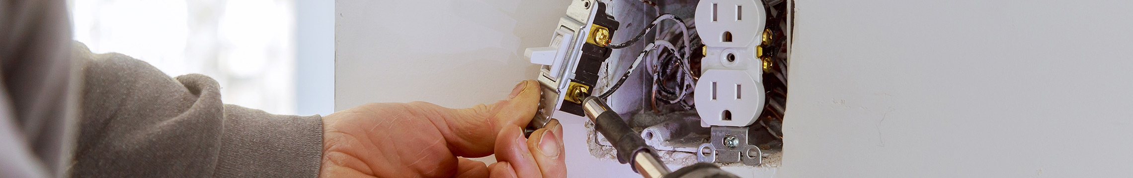 Handyman disassembling an electrical outlet in the wall