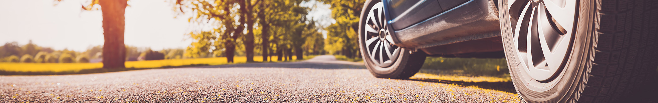 Blue car driving on a paved road on a sunny day