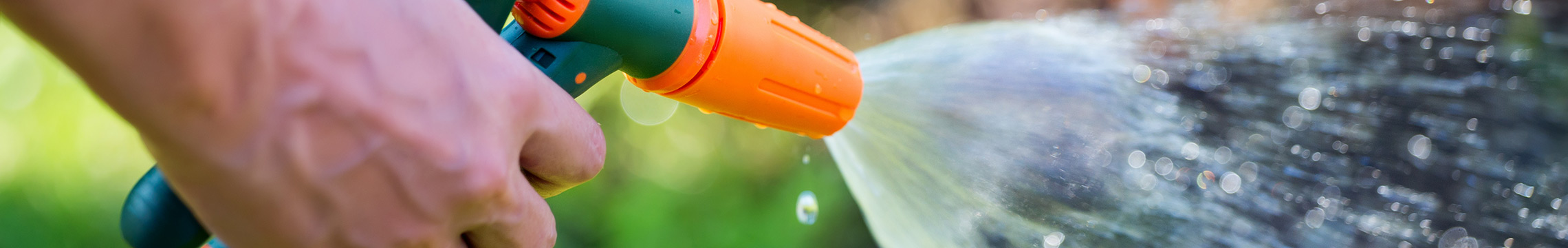 Water spraying from an orange and green hose sprayer spout