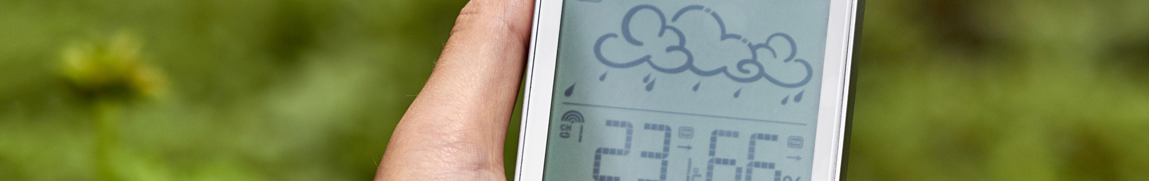 Digital thermometer being held to display the weather stats