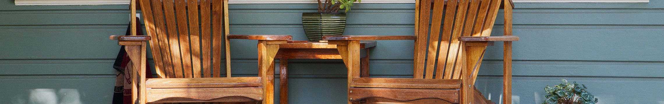 Wooden Adirondack chairs on a shaded porch