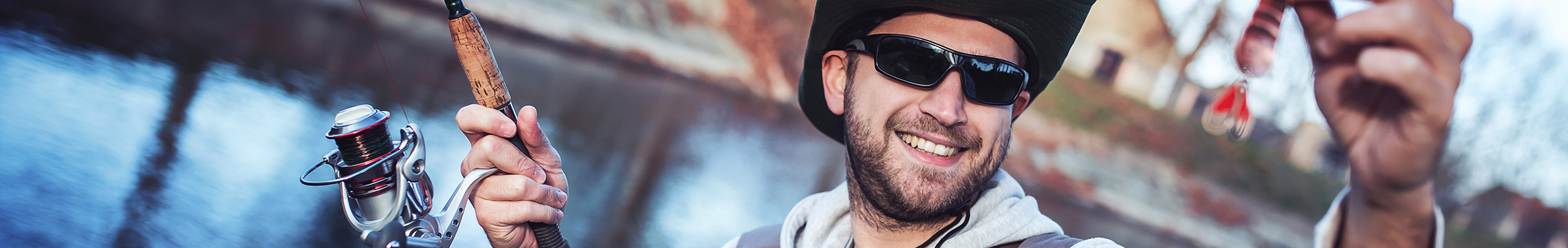 Man wearing sunglasses holds fishing gear toward camera