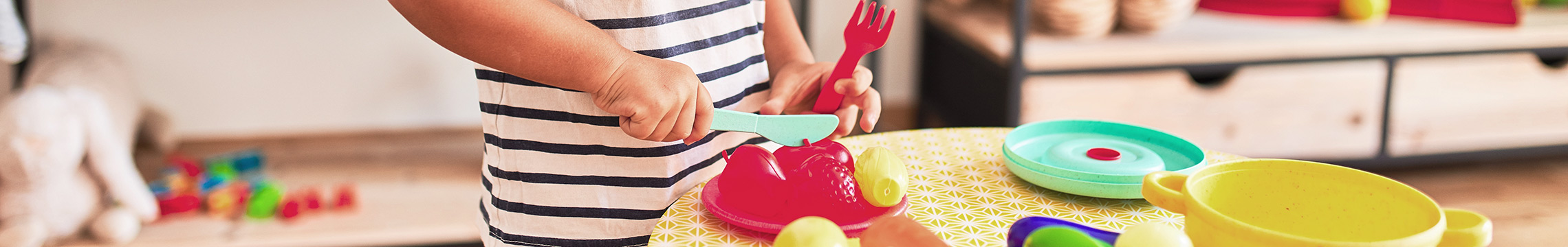Little boy prepares a brightly colored meal with a play set of food
