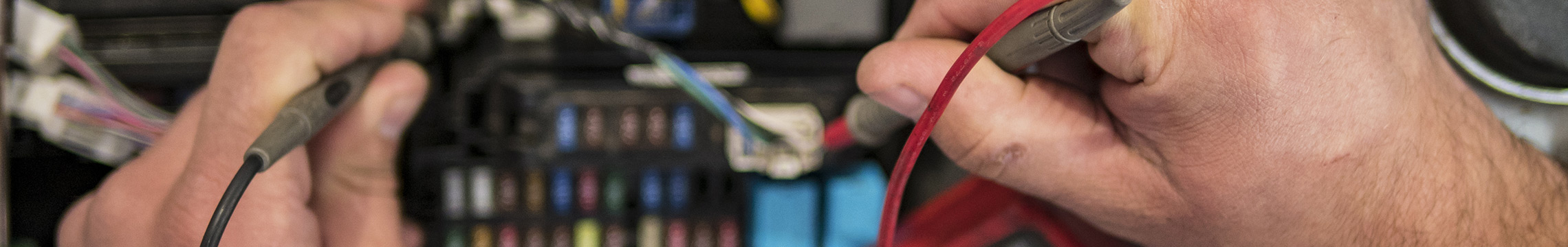 Mechanic testing electrical panel in vehicle