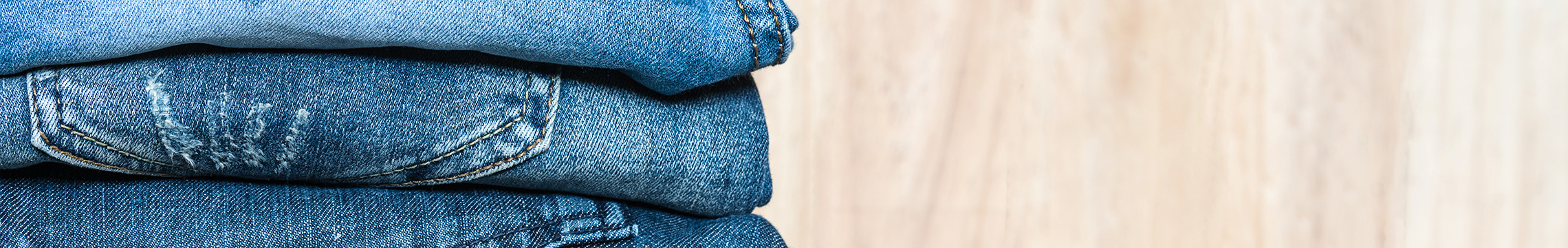 Folded women's blue jeans stacked neatly on a wooden table