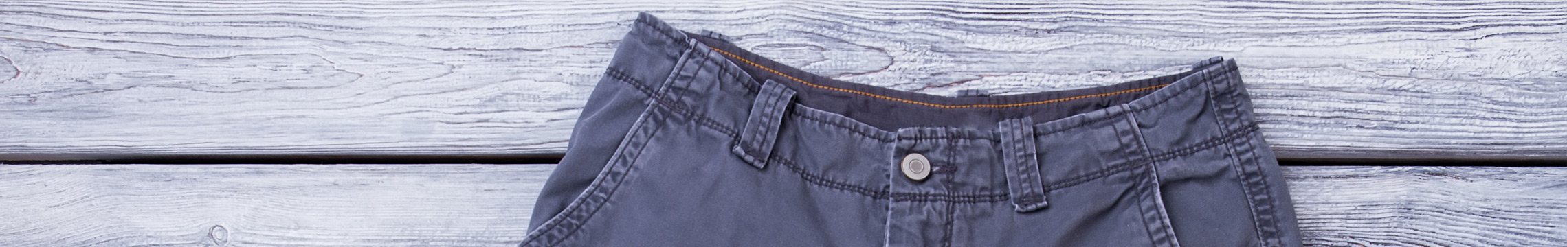 Grey cargo shorts laid gently across a white washed wooden background