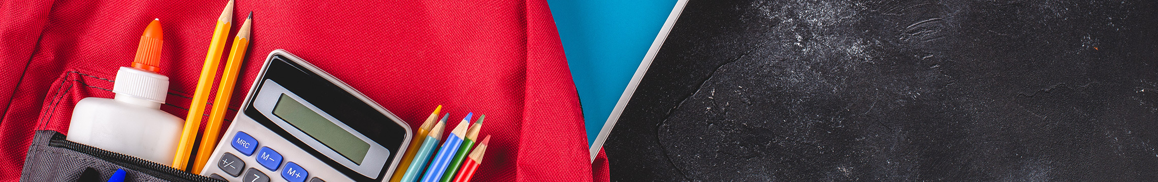 Red backpack filled with school supplies against a chalkboard background
