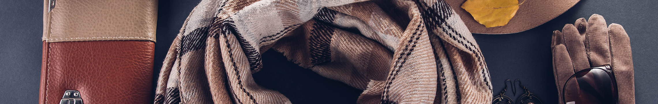 Plaid scarf displayed next to neutral colored accessories 