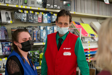 Clerk and manager behind counter talking to customer