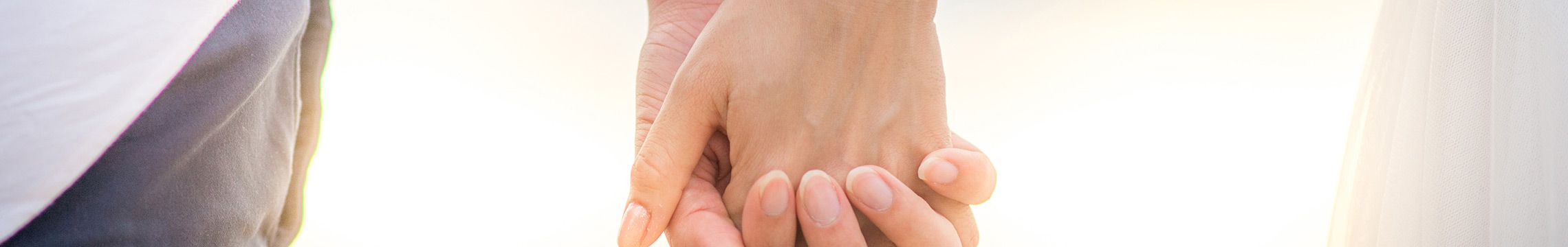 Couple romantically holding hands with interlaced fingers