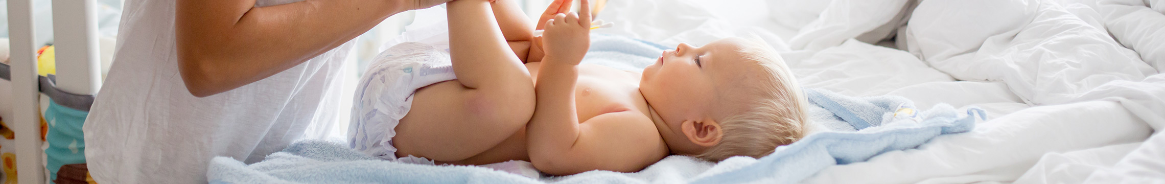 Mother changing baby's diaper on soft, blue blanket