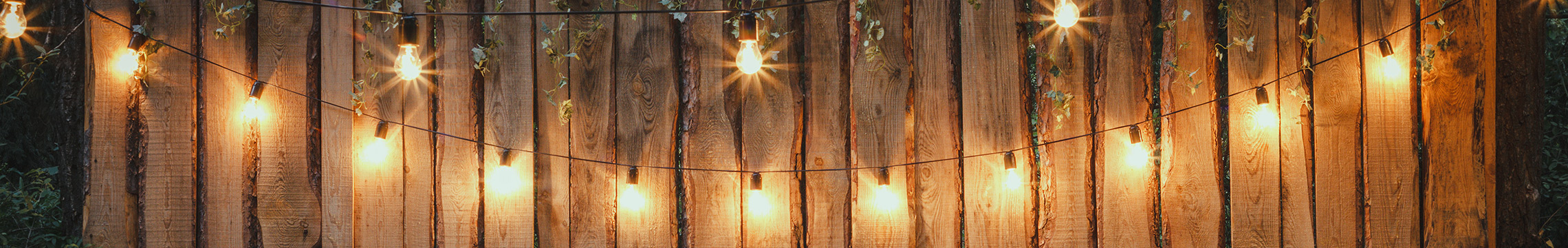 String of lights glowing against a wooden fence in back yard