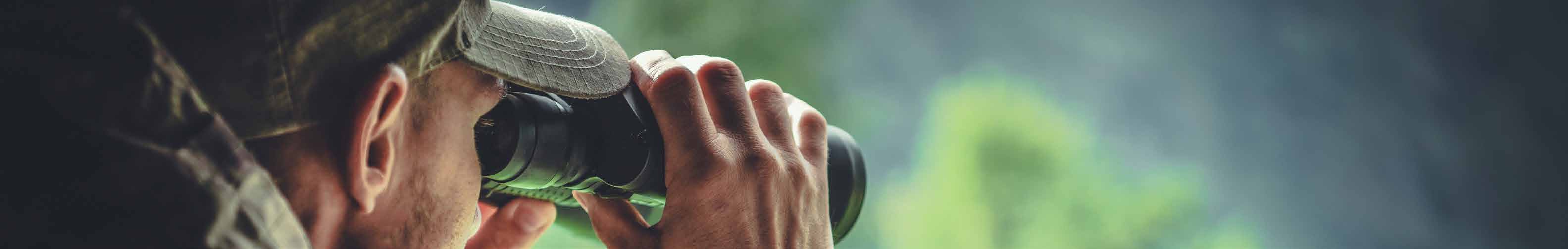 Person looking through binoculars on a outdoor scenic background