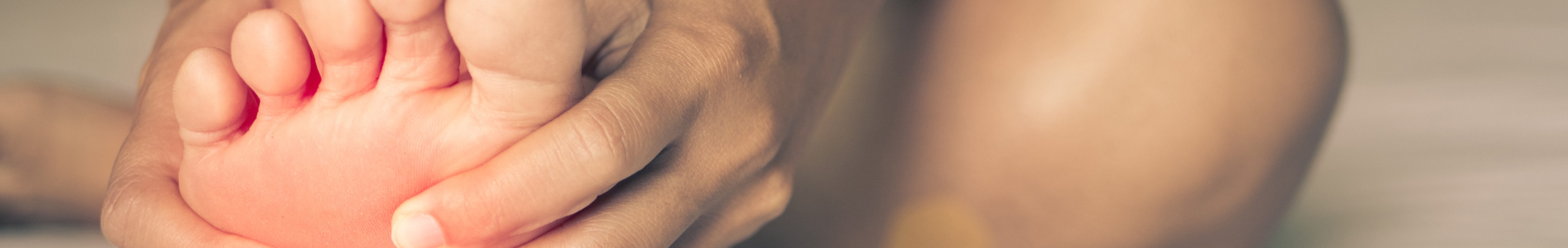 Woman massaging soul of their foot while flexing toes in pain