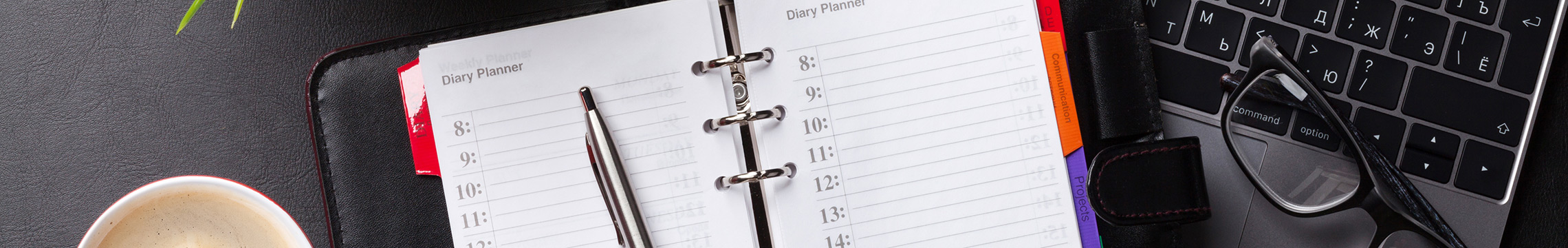 Professional looking day planner sitting open on a desk next to a cup of coffee and pair of glasses