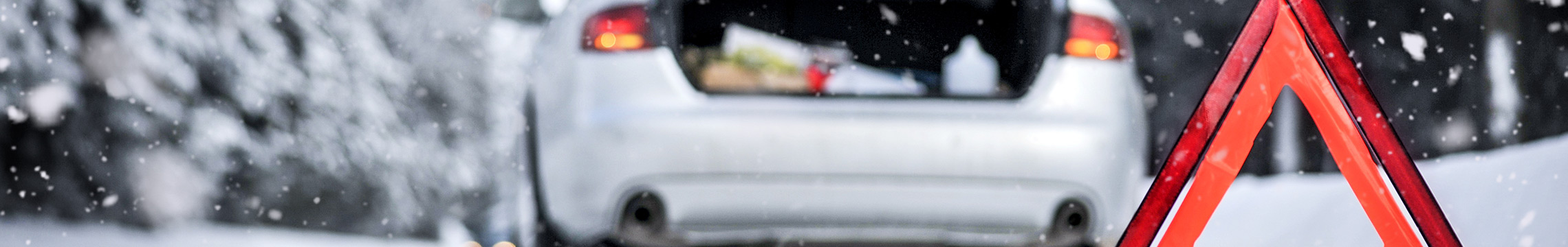 White car pulled over on icy road with safety cones nearby