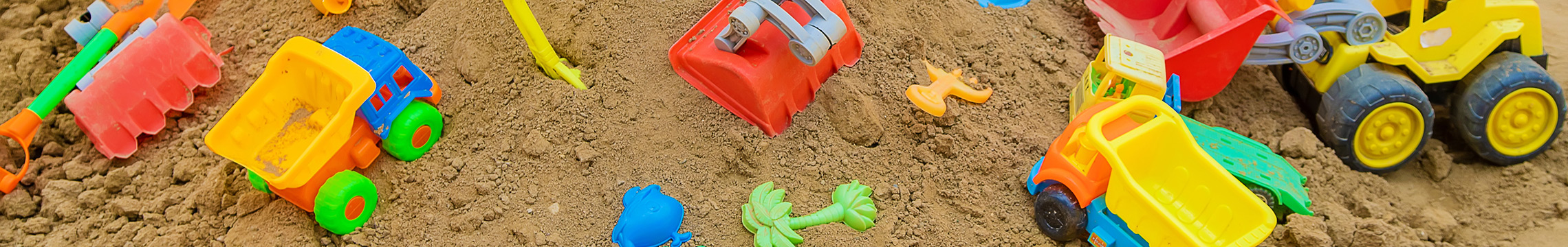 Variety of plastic sand toys scattered across a sand box