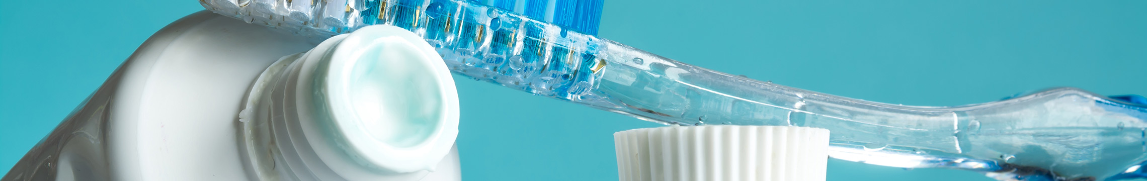 Toothbrush and toothpaste propped up together with a blue background