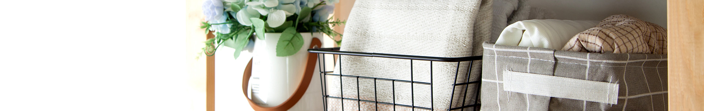 Linens folded and set into wire storage baskets on a wooden bookshelf