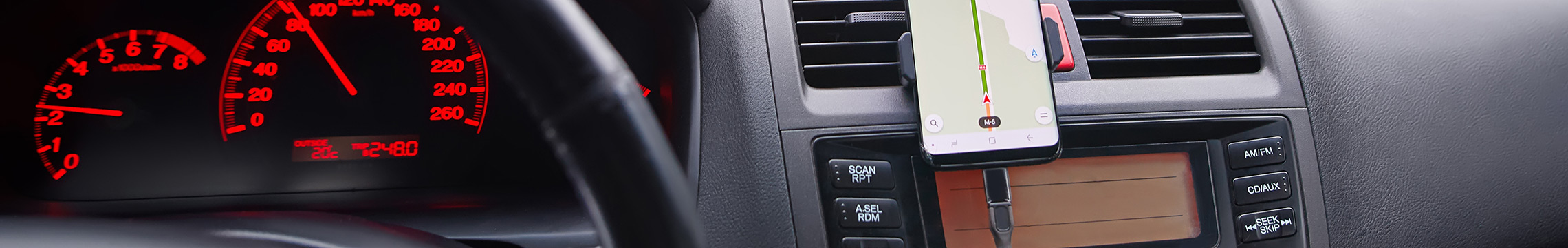 Cell phone mounted to dashboard while charging in car outlet