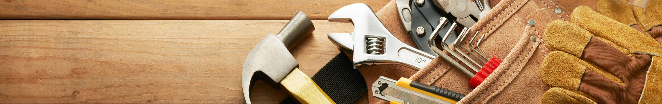 Suede toolbelt filled with assorted tool, against a wood panel background