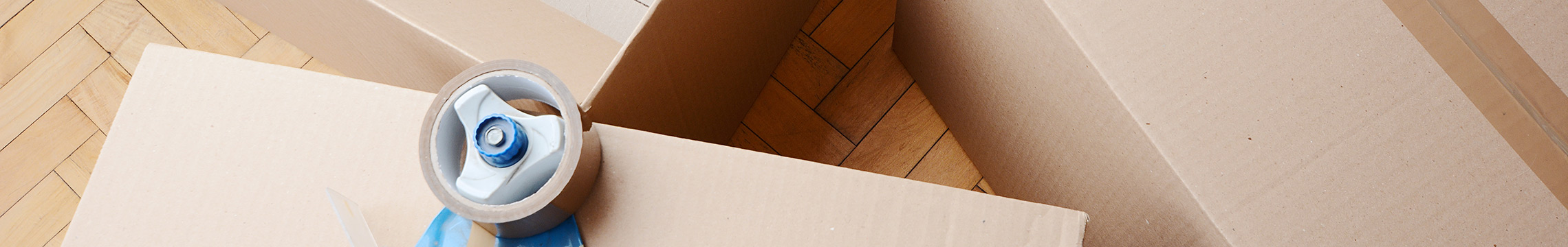 Packaging tape dispenser set on top of cardboard boxes being prepped for shipping