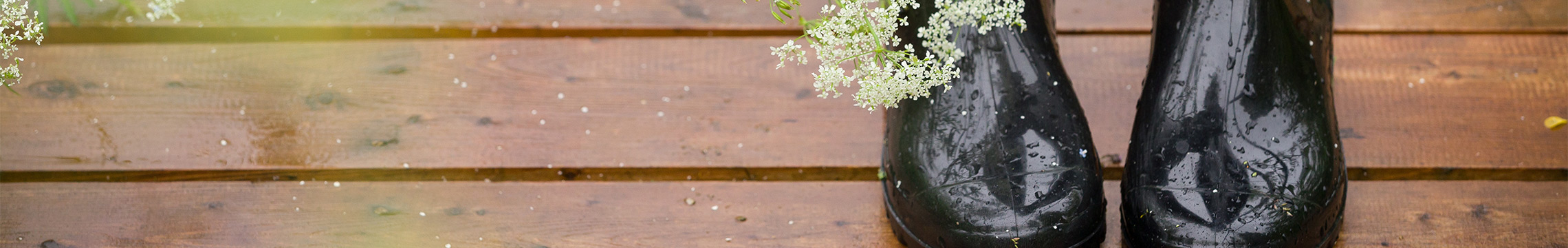 Shiny black women's rainboots on a wooden deck