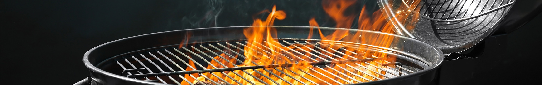 Black kettle barbecue with flames rising from the grill