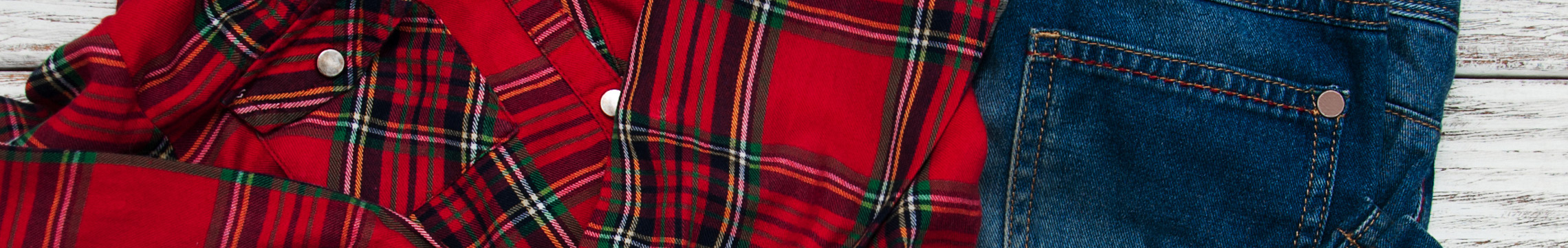 A red plaid shirt is laid out with a pair of blue jeans