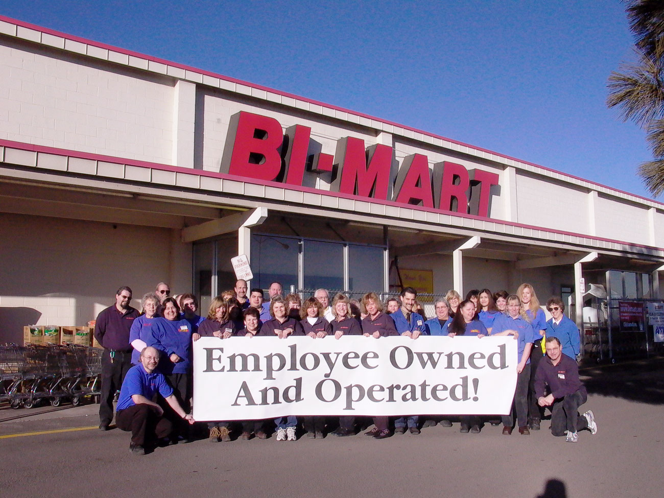 Bi-Mart Employees outside store with banner that says Employee Owned