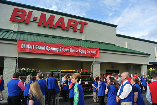 Employees surrounding  the store front at a Bi-Mart grand opening